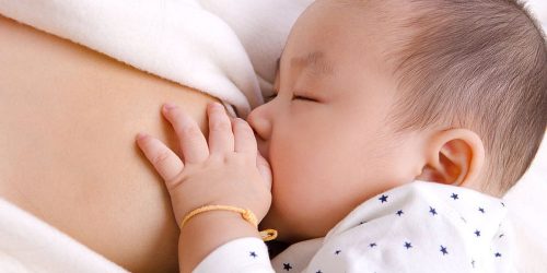 Six months old baby boy drinking breastmilk